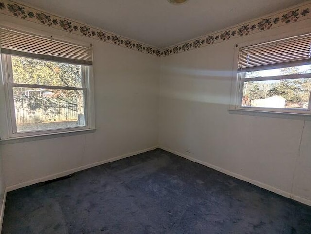 unfurnished room with dark carpet and baseboards