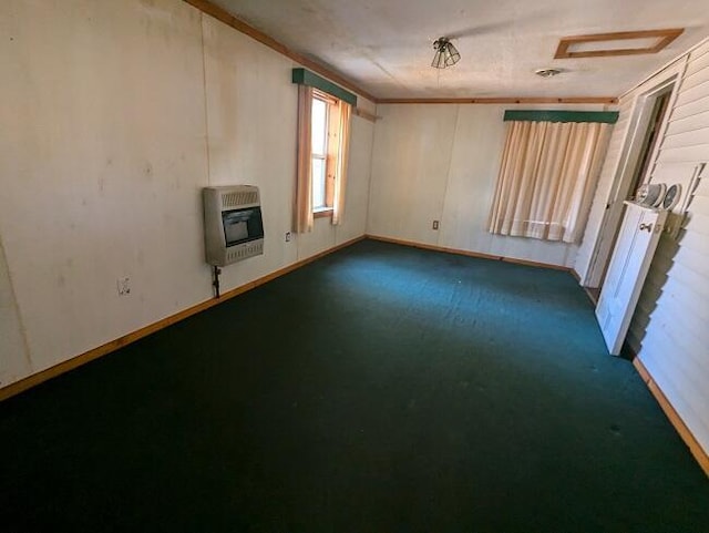 unfurnished room with attic access, dark colored carpet, and heating unit