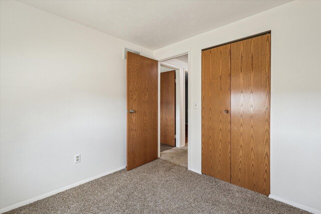 unfurnished bedroom with visible vents, baseboards, carpet flooring, and a closet