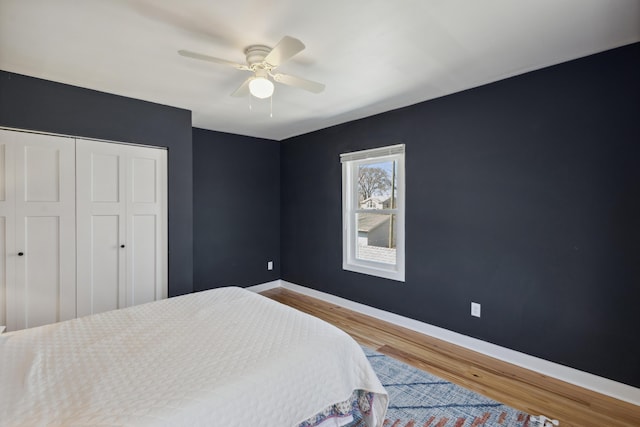 bedroom with wood finished floors, a closet, baseboards, and ceiling fan