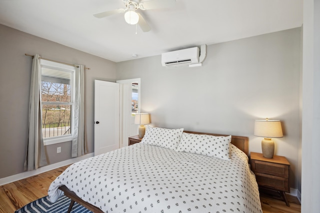 bedroom with baseboards, wood finished floors, and a wall unit AC