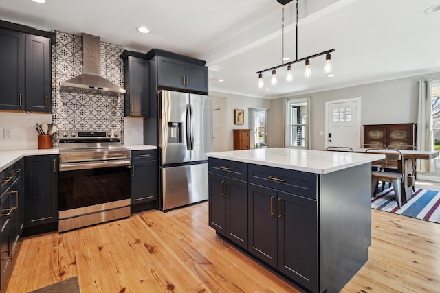 kitchen featuring ornamental molding, light wood-style floors, appliances with stainless steel finishes, and wall chimney range hood