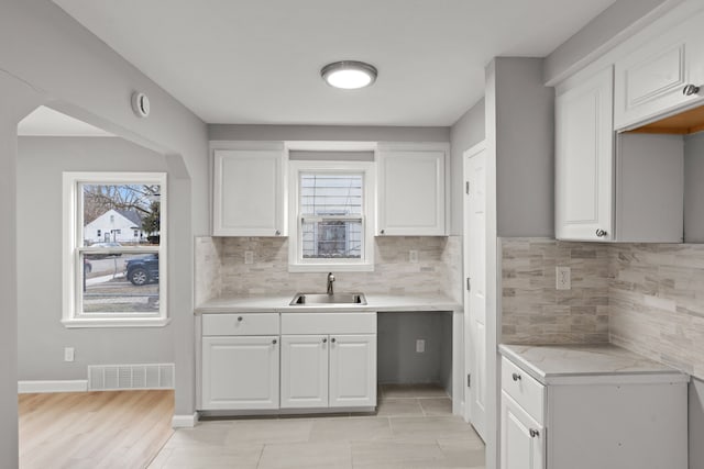 19319 Huntington Rd, Detroit, MI 48219 - kitchen with light countertops, backsplash, visible vents, a sink, and white cabinetry