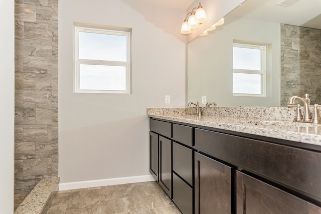 5192 Rolling Hills Dr, Grand Blanc, MI 48439 - bathroom featuring a sink, double vanity, a tile shower, visible vents, and baseboards