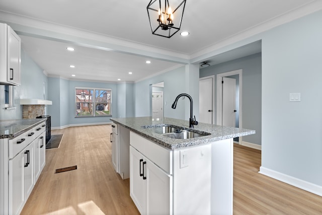 19319 Pennington Dr, Detroit, MI 48221 - kitchen with light wood finished floors, white cabinets, a sink, and dark stone countertops