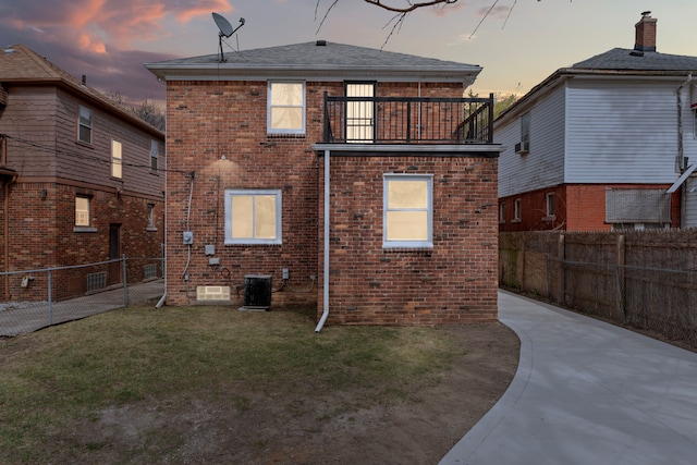 19319 Pennington Dr, Detroit, MI 48221 - back of property at dusk featuring a fenced backyard, central air condition unit, brick siding, a lawn, and a balcony