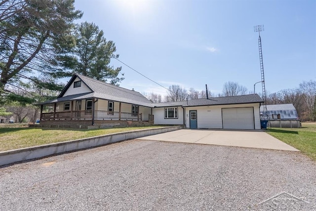 view of front of home with gravel driveway, a front lawn, and an attached garage