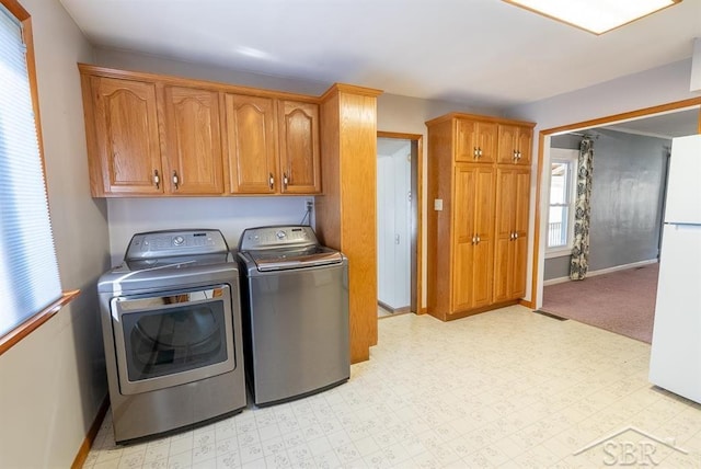 laundry area featuring light floors, visible vents, washing machine and dryer, baseboards, and cabinet space