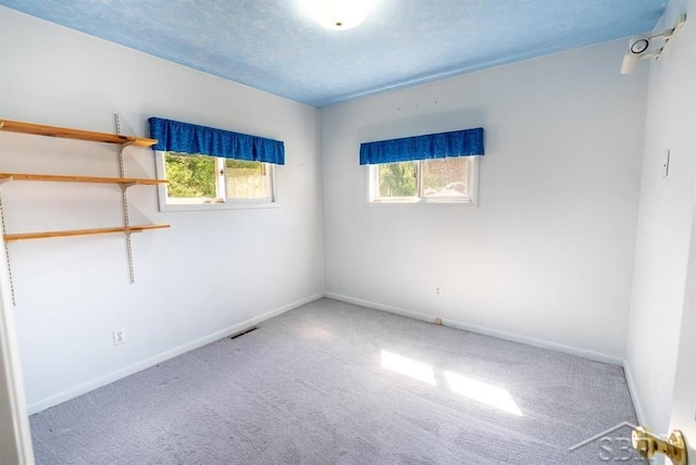 carpeted empty room with visible vents and baseboards
