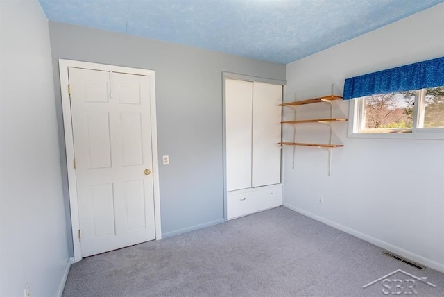 unfurnished bedroom featuring baseboards, visible vents, carpet floors, and a closet
