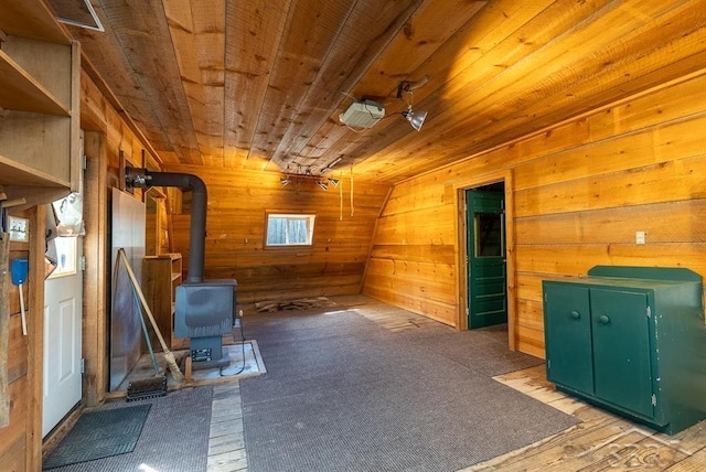 interior space featuring wooden ceiling, a wood stove, and wooden walls