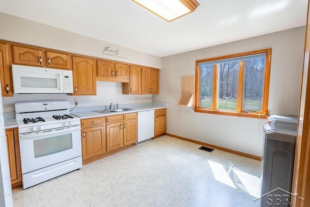 kitchen featuring light countertops, visible vents, a sink, white appliances, and washer / clothes dryer