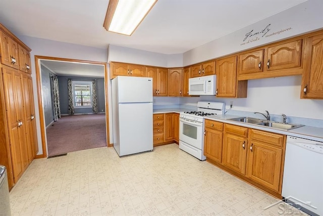 kitchen with a sink, brown cabinetry, white appliances, light countertops, and baseboards