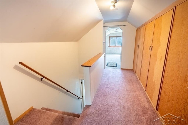 hallway featuring vaulted ceiling, light colored carpet, and an upstairs landing