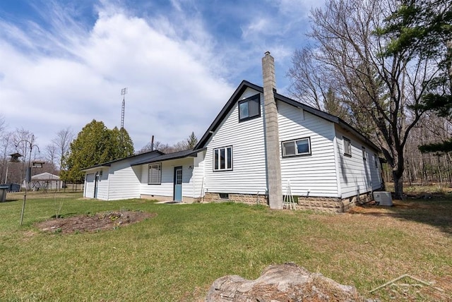 back of house with a chimney, a yard, and central AC unit