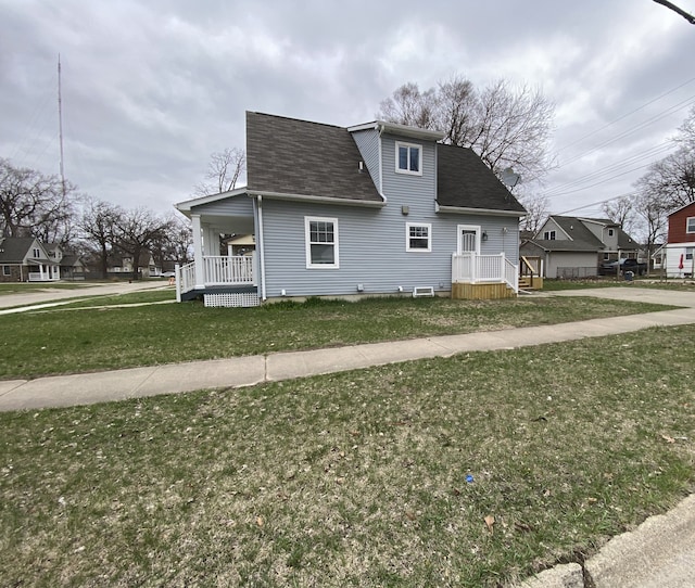 view of front of home featuring a porch, a shingled roof, and a front yard