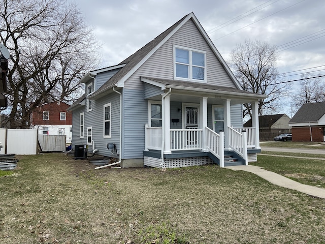 bungalow-style home with fence, covered porch, a front yard, and central AC unit