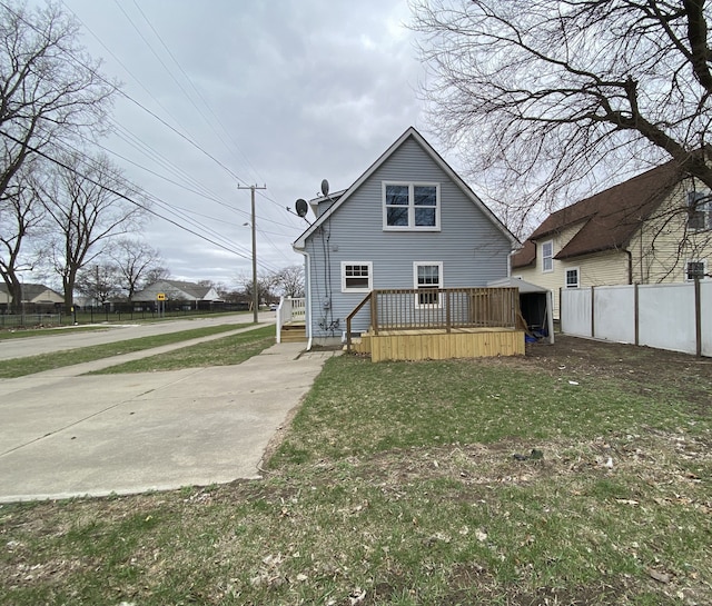 back of house with a wooden deck, a lawn, and fence