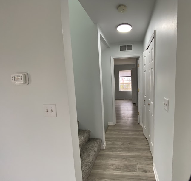 corridor with stairway, baseboards, wood finished floors, and visible vents