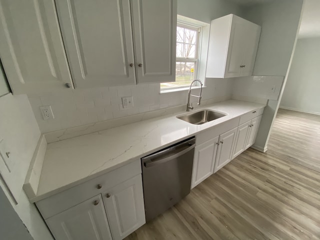 kitchen featuring white cabinets, light wood-type flooring, stainless steel dishwasher, and a sink