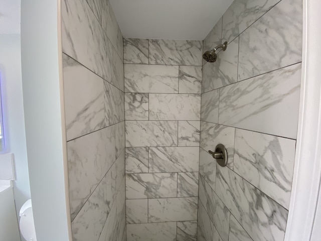 full bathroom featuring toilet and tiled shower