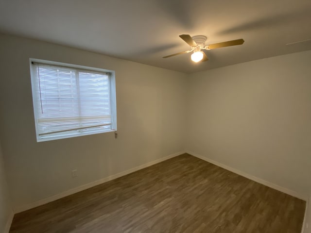 empty room featuring baseboards, a ceiling fan, and dark wood-style floors