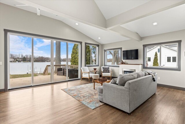living room with recessed lighting, lofted ceiling, wood finished floors, a water view, and a fireplace