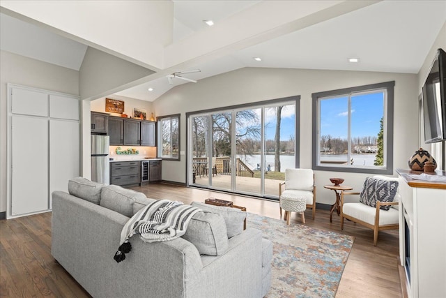living area with vaulted ceiling, wood finished floors, a bar, and recessed lighting