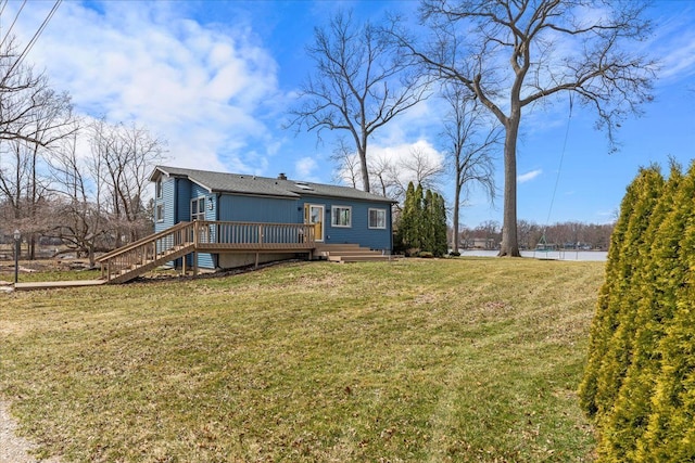 rear view of house with stairway, a lawn, and a deck with water view