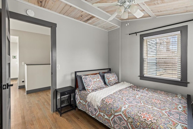bedroom featuring beam ceiling, wood finished floors, ceiling fan, crown molding, and wooden ceiling