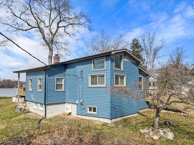 view of side of property featuring a lawn and a chimney