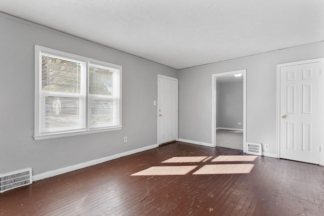 unfurnished bedroom with hardwood / wood-style flooring, baseboards, and visible vents