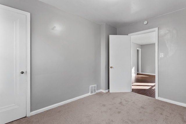 carpeted empty room featuring visible vents and baseboards