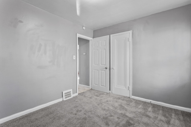 unfurnished bedroom with carpet, visible vents, and baseboards