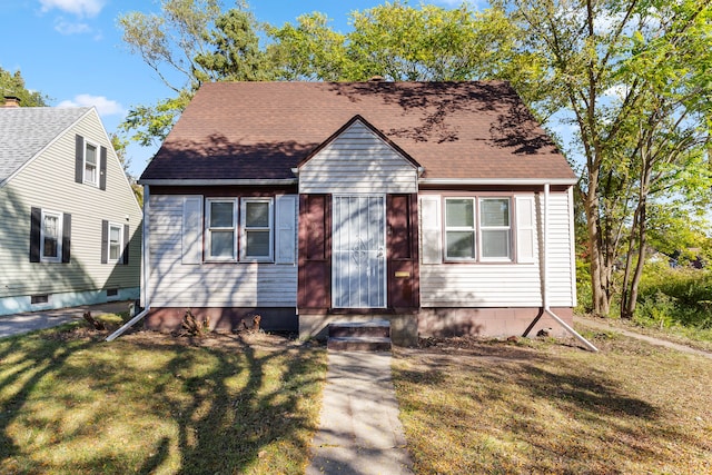 view of front of property featuring a front lawn and roof with shingles