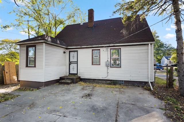 back of house featuring a shingled roof, a chimney, and fence