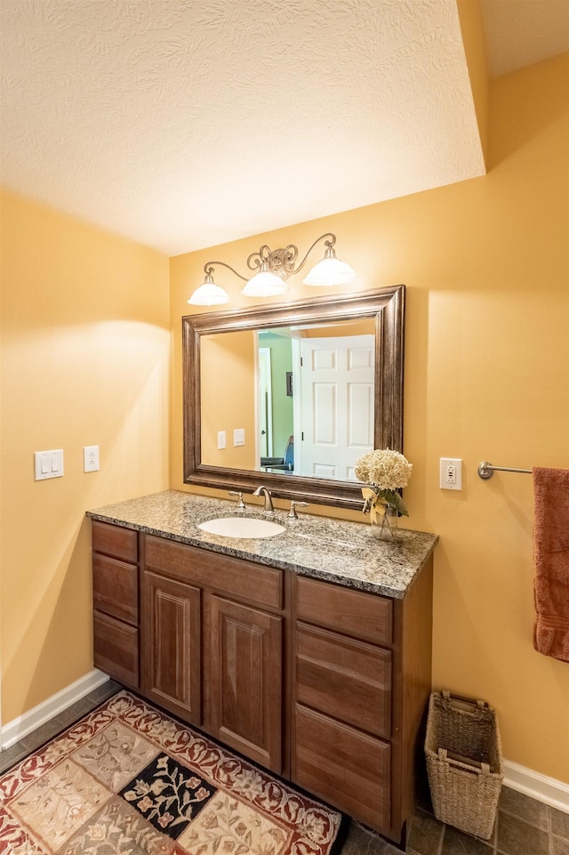 bathroom with baseboards, a textured ceiling, and vanity