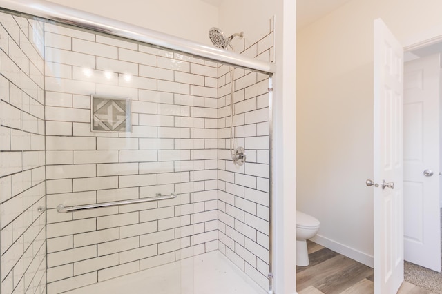 bathroom featuring a shower stall, toilet, and wood finished floors