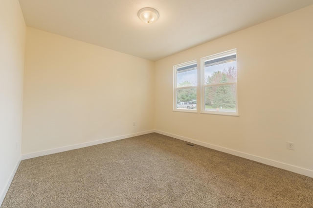 carpeted empty room featuring baseboards