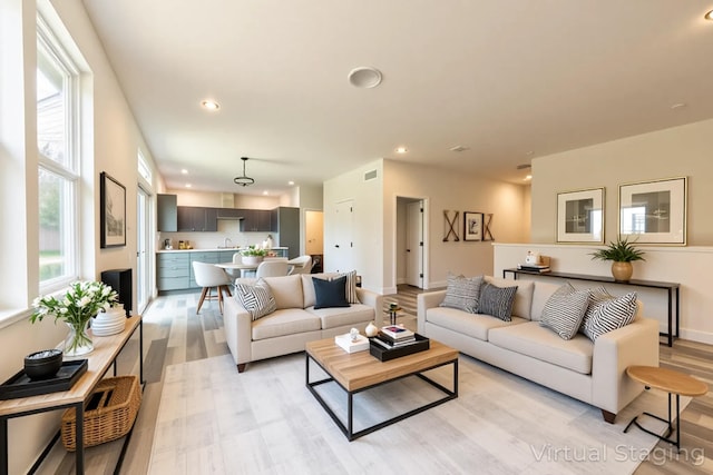 living room featuring light wood-type flooring, recessed lighting, and baseboards