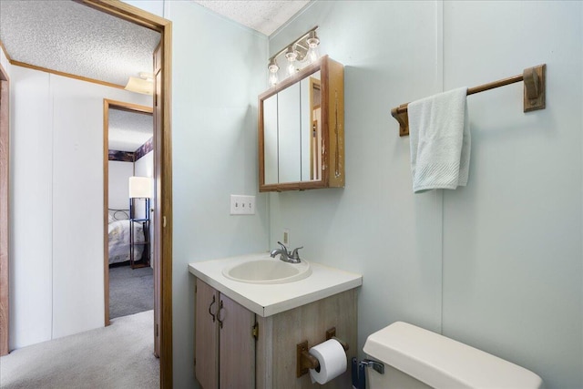 half bathroom with toilet, vanity, and a textured ceiling