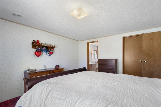 bedroom featuring a textured ceiling, connected bathroom, and crown molding