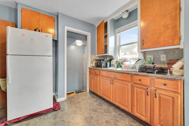 14424 Edmore Dr, Detroit, MI 48205 - kitchen with dark stone countertops, a sink, brown cabinetry, decorative backsplash, and freestanding refrigerator