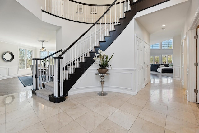 stairway with tile patterned floors, a high ceiling, a decorative wall, and a chandelier