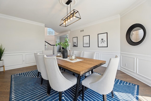dining room featuring visible vents, ornamental molding, wainscoting, a decorative wall, and dark wood-type flooring