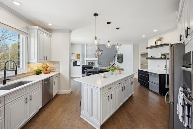 kitchen with white cabinets, a sink, a large fireplace, decorative backsplash, and stainless steel dishwasher