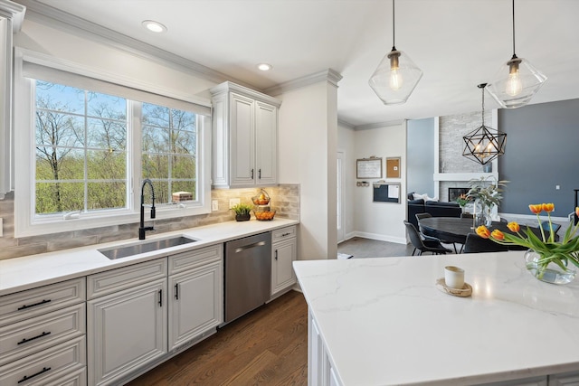 kitchen featuring dishwasher, dark wood-style floors, a large fireplace, a sink, and backsplash