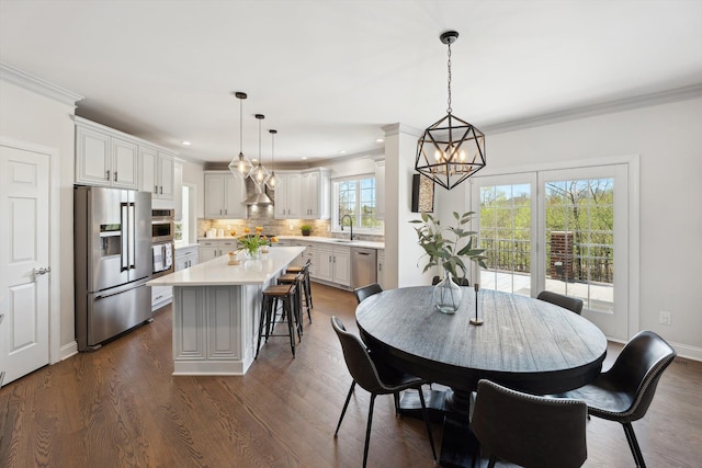 dining area with an inviting chandelier, ornamental molding, recessed lighting, and dark wood finished floors