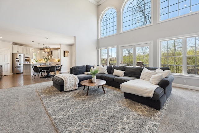 living room featuring baseboards, ornamental molding, and a high ceiling