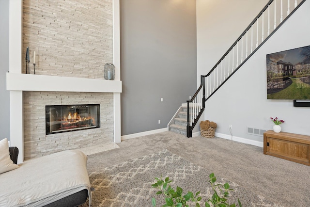 carpeted living room featuring stairs, a high ceiling, visible vents, and baseboards